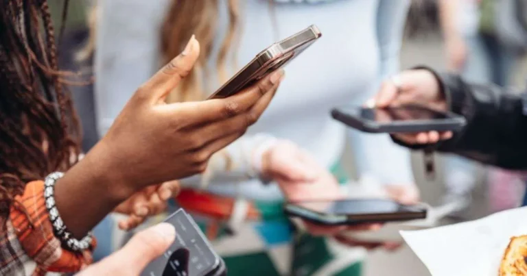 Group of people using smartphones in close proximity.